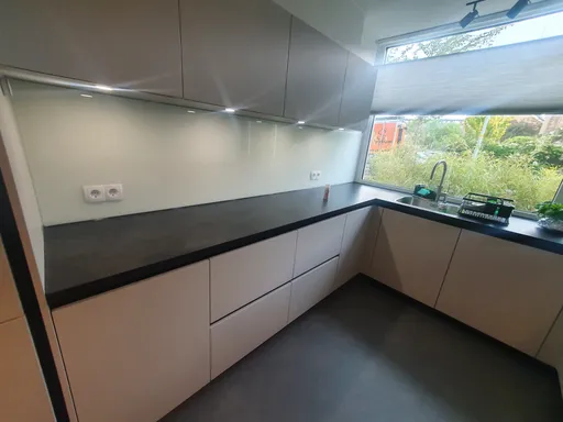 Een keuken met een glazen achterwand